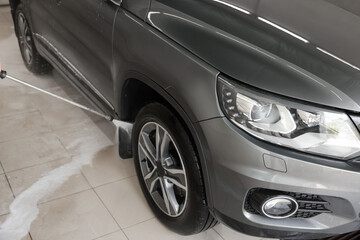 Washing auto with high pressure water jet at car wash, closeup