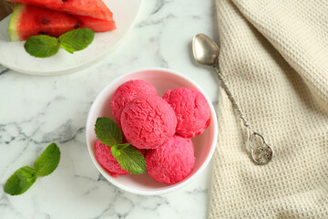 Scoops of tasty watermelon sorbet with mint in bowl and spoon on white marble table, flat lay