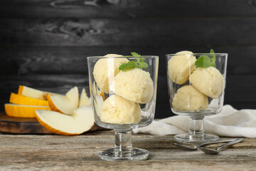 Scoops of melon sorbet in glass dessert bowls and spoons on wooden table
