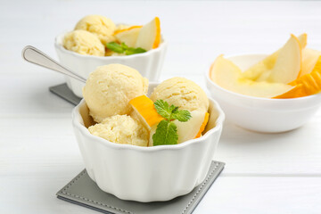 Scoops of melon sorbet with mint and fresh fruit in bowls on white wooden table, closeup