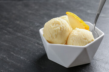 Scoops of tasty melon sorbet with fresh fruit and spoon in bowl on grey textured table, closeup. Space for text