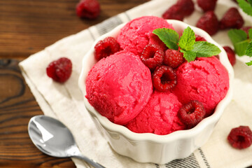 Delicious raspberry sorbet with fresh berries in bowl and spoon on wooden table, closeup