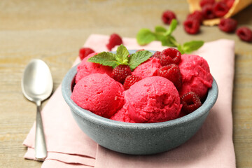 Delicious raspberry sorbet with fresh berries in bowl and spoon on wooden table, closeup