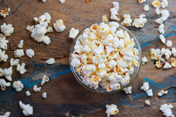 Salted popcorn in a glass bowl at the old wooden table