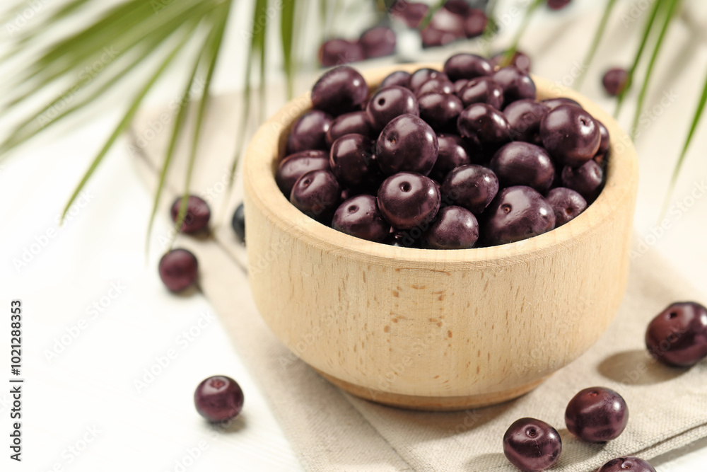 Wall mural ripe acai berries in bowl on white table, closeup