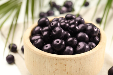 Ripe acai berries in bowl on table, closeup