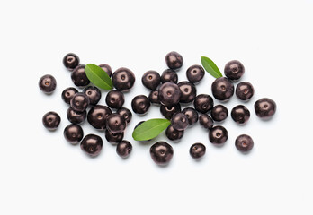 Ripe acai berries and leaves on white background, flat lay