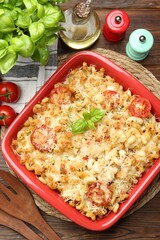 Delicious al forno pasta in baking dish on wooden table, flat lay