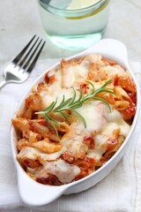 Delicious al forno pasta in baking dish on light table, closeup