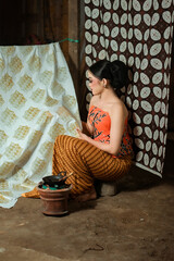 Fototapeta premium Young Indonesian women or fashion models wearing traditional Indonesian clothing or attire with batik motifs from Indonesian culture. Making or painting batik cloth. Making batik cloth.