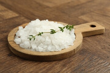 Sea salt and thyme on wooden table, closeup
