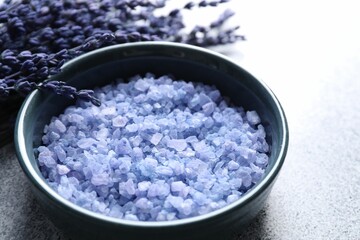 Natural sea salt and lavender flowers on grey table, closeup