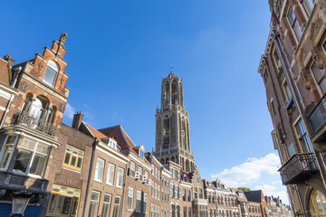 Fototapeta premium Dom Tower in Utrecht surrounded by historic buildings and a blue sky.