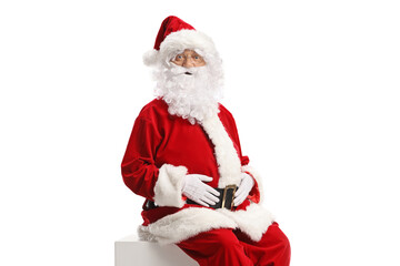 Santa claus sitting on a white cube and looking at camera