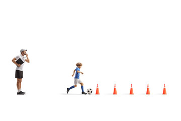 Coach whistling and a boy leading a football between obstacle cones