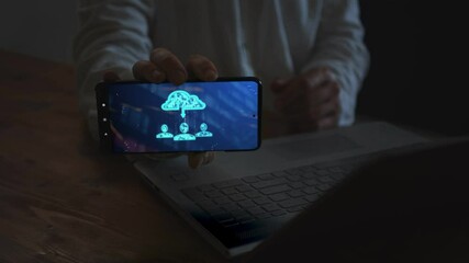 A businessman working on a laptop and with a smartphone demonstrates a symbolic group of people with a cloud of information storage and binary code numbers moving between them. Cg - Powered by Adobe