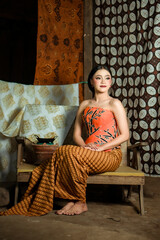 Fototapeta premium Young Indonesian women or fashion models wearing traditional Indonesian clothing or attire with batik motifs from Indonesian culture. Making or painting batik cloth. Making batik cloth.