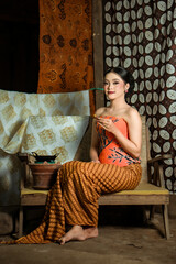Fototapeta premium Young Indonesian women or fashion models wearing traditional Indonesian clothing or attire with batik motifs from Indonesian culture. Making or painting batik cloth. Making batik cloth.
