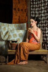 Fototapeta premium Young Indonesian women or fashion models wearing traditional Indonesian clothing or attire with batik motifs from Indonesian culture. Making or painting batik cloth. Making batik cloth.