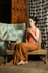 Fototapeta premium Young Indonesian women or fashion models wearing traditional Indonesian clothing or attire with batik motifs from Indonesian culture. Making or painting batik cloth. Making batik cloth.