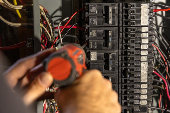 Electrician is installing an electrical circuit breaker in a power panel using a screwdriver. Selective focus