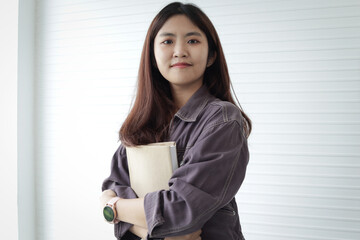 Portrait of Asian high school girl student holding book, standing in classes. Female student engages in study. Happy college pupil spending time learning. University kid with senior education.