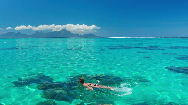 Snorkeling woman in stunning lagoon with turquoise water and mountain backdrop, perfect for tropical island getaway. Enjoy swimming in tranquil coral reef paradise