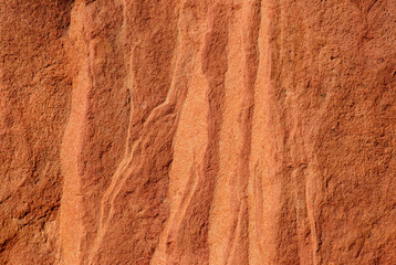 Close-up of red sandstone rock texture featuring natural wavy patterns and rough surface.