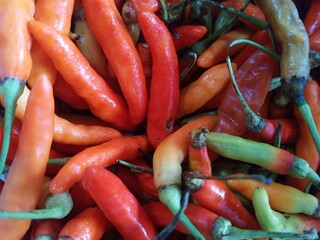 A pile of red rawit chilies, captured in a macro shot with a shallow depth of field, emphasizing their intricate details.