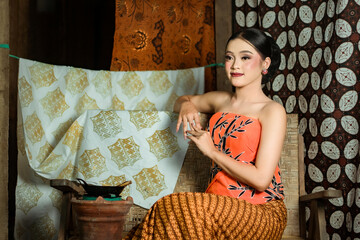 Fototapeta premium Young Indonesian women or fashion models wearing traditional Indonesian clothing or attire with batik motifs from Indonesian culture. Making or painting batik cloth. Making batik cloth.