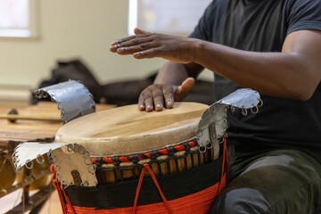 Close up of a percussionist playing a djembe drum with his hands, hitting the skin with his palms...
