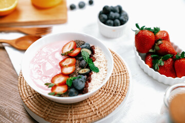 Presented by fruits putting yogurt toppings with strawberry, berry, oats, raisins and chia seed decorated by peppermint in white blow. Pink background. Set of healthy dairy product choice. Pecuniary.