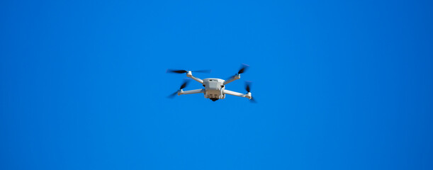 Quadcopter in flight against the sky. A small drone takes off above the ground.