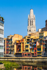 Obraz premium Clocher de style gothique de la Basílica Sant Feliu de Gérone dominant le Riu Onyar et ses immeubles colorés