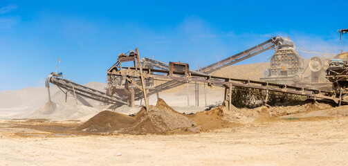 Vibrating screen stone crusher in operation. Crushing stones in a quarry for processing minerals, cement, limestone. Heavy and mobile equipment in a quarry for processing stone into building material.