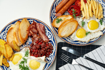 Two plates of a hearty breakfast served on decorative bowls