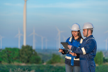 engineers working and holding the report at wind turbine farm Power Generator Station on mountain,Thailand people,Technician man and woman discuss about work