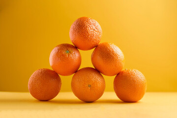 a pile of Oranges on a bright yellow background