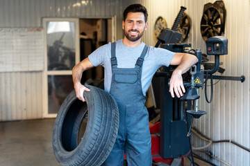 Mechanic holding a tire and smiling in a mechanical workshop