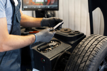 Mechanic holding wheel balancing weight in a garage