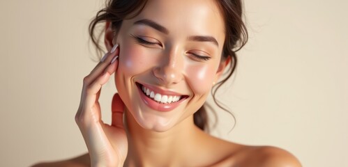Fototapeta premium A young woman smiles radiantly while touching her face, showcasing healthy skin and natural beauty, perfect for beauty, skincare, wellness, and lifestyle themes.