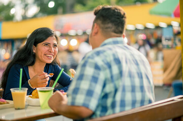 Friends chatting happily, sitting at a street food stall.