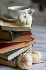 Small colorful pumpkins, coffee and a lot of books on the table, autumn mood.
