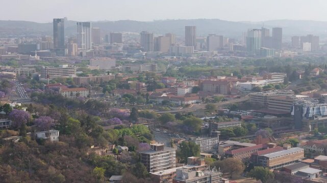 Aerial view of smoggy Pretoria city business district. Two government hospitals and traffic visible in foreground 