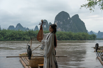 Hanfu girl with pipa instrument posing for a photographer on board of small wooden raft, China