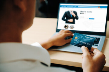 Young man use credit card for shopping payment online on laptop computer application or website. E-commerce and online shopping concept. uds
