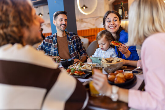 Family and friends gathered in a restaurant to eat delicious food, talk, drink and hang out.