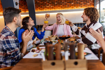 Family and friends gathered in a restaurant to eat delicious food, talk, drink and hang out.