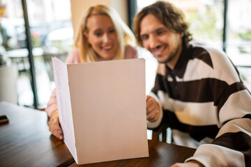 Couple went on a date in a restaurant. They read the menu and choose what to order.