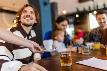 Waiter bringing coffee to his customer in a restaurant.